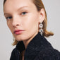 Woman with short blonde hair wearing Pilgrim's ACT earrings, showcasing their unique silver-plated design with organic shapes, made from 97% recycled material.