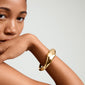 Close-up of a woman's wrist wearing the gold-plated DUNE bangle by Pilgrim, showcasing its chunky, uneven design and handcrafted elegance.