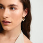 DUNE crystal earrings gold-plated: Close-up of woman wearing gold chunky hoop earrings with heart charms and crystals, highlighting their shiny, romantic design.