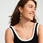 Woman smiling, showcasing Pilgrim's TIDE gold-plated earrings with heart shapes, highlighting style and eco-conscious fashion from recycled materials.