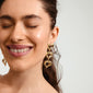 Gold-plated TIDE earrings with organically shaped hearts, worn by a smiling woman. Part of Pilgrim's trendy, eco-friendly jewellery collection.