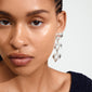 Close-up of a woman wearing Pilgrim's TIDE silver-plated earrings, featuring rows of heart shapes, showcasing a stylish and eco-friendly accessory.