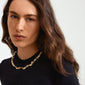 Woman wearing Pilgrim's gold-plated SUNSET necklace with a unique, wavy design, highlighting its sophisticated, chic style.