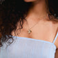 Gold-plated DREAM necklace with a floral pendant, inspired by nature's beauty, worn by a woman, showcasing Pilgrim's unique, eco-friendly style.