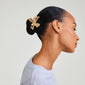 Profile of a woman wearing the DREAM hair accessory, featuring a gold-plated flower clip, perfect for enhancing summer hairstyles like messy buns or high ponytails.