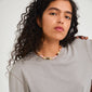 Woman with curly hair wearing the DREAM necklace multi/gold-plated, featuring stones and glass beads, reflecting elegant summer vibes from Pilgrim.