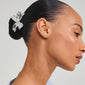 Woman's profile showcasing the DREAM hair accessory silver-plated, featuring a large flower charm in a stylish bun, embodying Pilgrim's eco-friendly, trendy design.