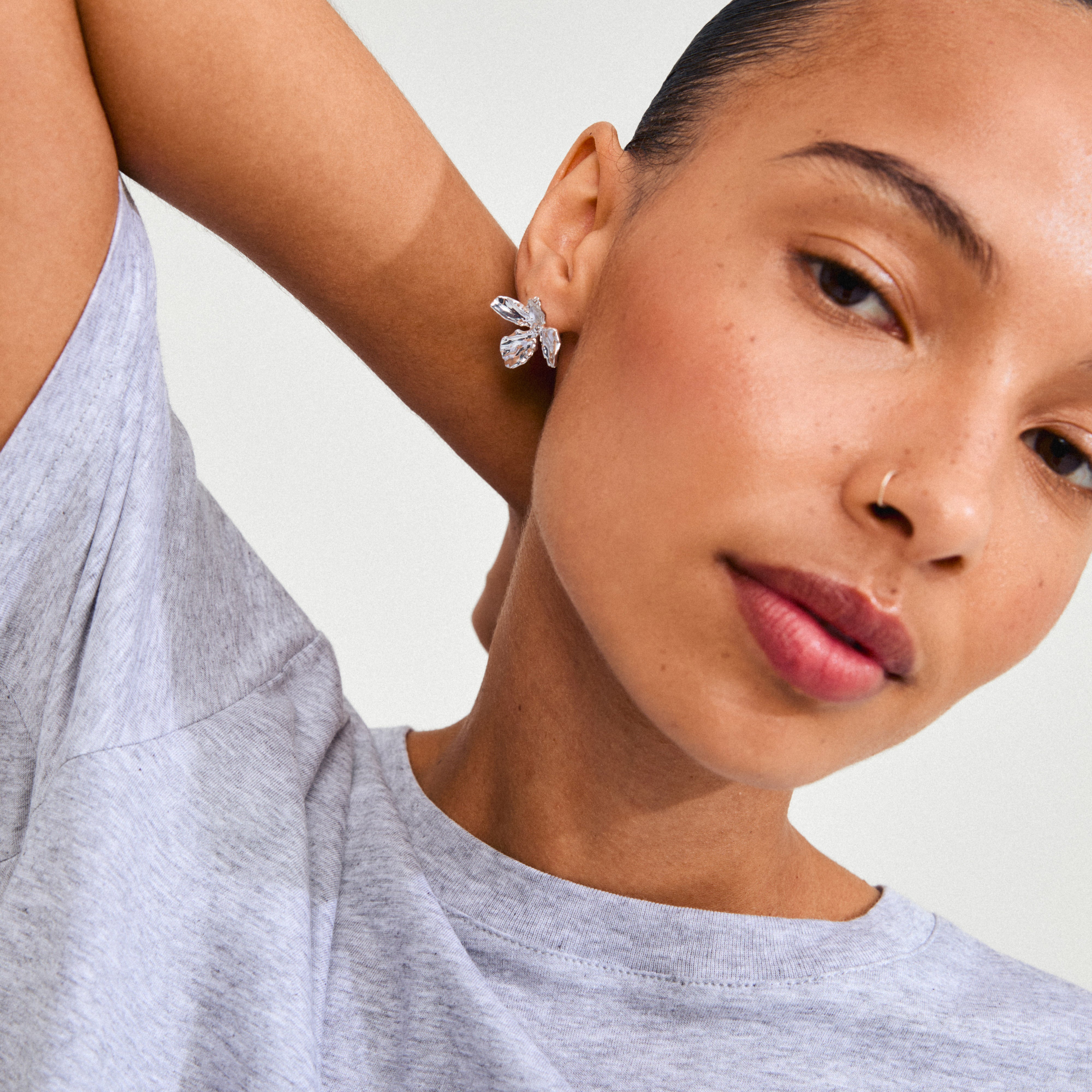 Close-up of a woman wearing silver-plated DREAM earrings by Pilgrim, featuring delicate flower design, showcasing charm and sophistication with a handcrafted feel.