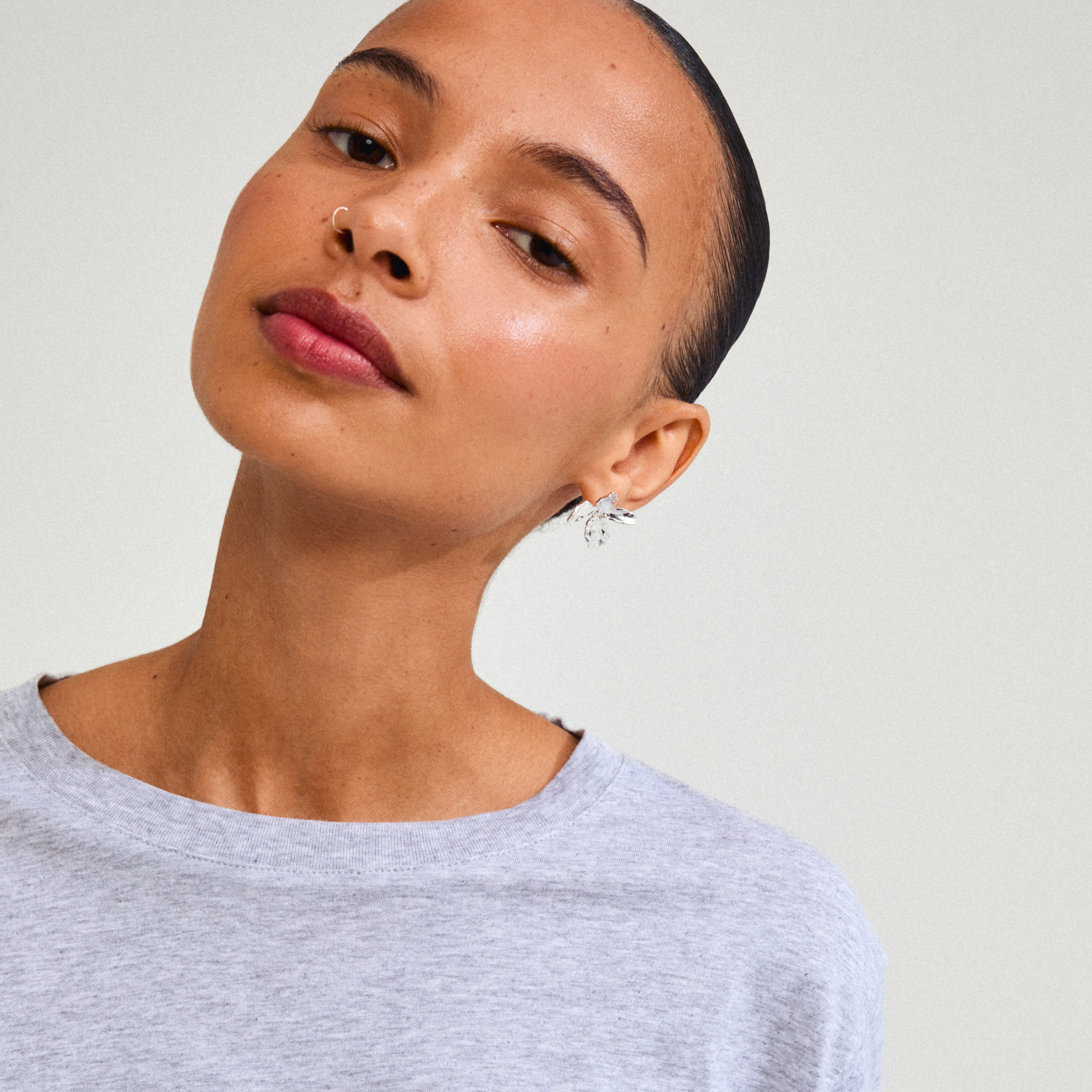 Close-up of a woman wearing Pilgrim's silver-plated DREAM earrings, featuring a floral design that embodies charm and sophistication.