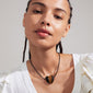 Woman wearing the STAY tiger eye necklace, featuring a silver-plated heart pendant on a black leather cord, showcasing an earthy, bohemian style.