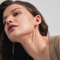 CONNECT earrings gold-plated with chain pendants creating a waterfall effect, worn by a woman with long hair, showcasing the earrings' elegant design.