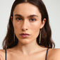 Woman wearing gold-plated SKY chain earrings from Pilgrim, featuring sleek chains and dazzling Preciosa crystals, highlighting sophisticated style.