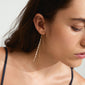 Woman wearing SKY chain earrings, gold-plated, featuring sleek chains and sparkling Preciosa crystals, showcasing sophisticated style. Perfect for adding glamor to any occasion.