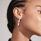 Close-up of a woman wearing CHARMAINE silver-plated earrings by Pilgrim, showcasing their flowery, oriental-inspired design.