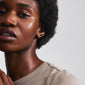 Close-up of a woman wearing the ZENA ear cuff gold-plated, showcasing its organic, handcrafted design that complements her curly hairstyle.