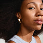 Close-up of a woman wearing Pilgrim's DUNE gold-plated earrings, showcasing their bold, chunky design and sophisticated elegance.