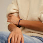 POWERSTONE bracelet featuring round Amethyst beads on a lycra elastic, worn by a person with a close-up of the wrist and hand.