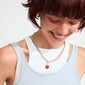 Woman smiling, wearing Pilgrim's CHARM agat heart pendant, gold-plated, featuring a red Agate heart, symbolizing protection and courage.