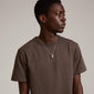 Man in brown shirt wearing Pilgrim's CHANTAL pendant necklace, silver-plated with an organic-shaped pendant and adjustable slim chain, displaying a simple, dynamic look.