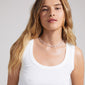 INAYA necklace silver-plated with organic links and white glass beads, worn by a woman in a white tank top, showcasing its elegant, sea-inspired design.