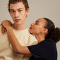 A woman embraces a man, showcasing Pilgrim's IOKASTE chunky hoops, gold-plated earrings with removable heart pendants.