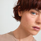 Woman with short red hair wearing CHARMAINE earrings, featuring gold-plated flower design, highlighting a nature-inspired, sustainable aesthetic from Pilgrim.