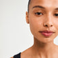 Close-up of a woman wearing EMANUELLE earrings 3-in-1 set, featuring crystal studs, rose gold-plated earrings, and twirly huggie hoops.