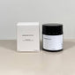 PILGRIM Scented candle in a black container with a white label, placed beside its white box, offering a relaxing Sandalwood fragrance.