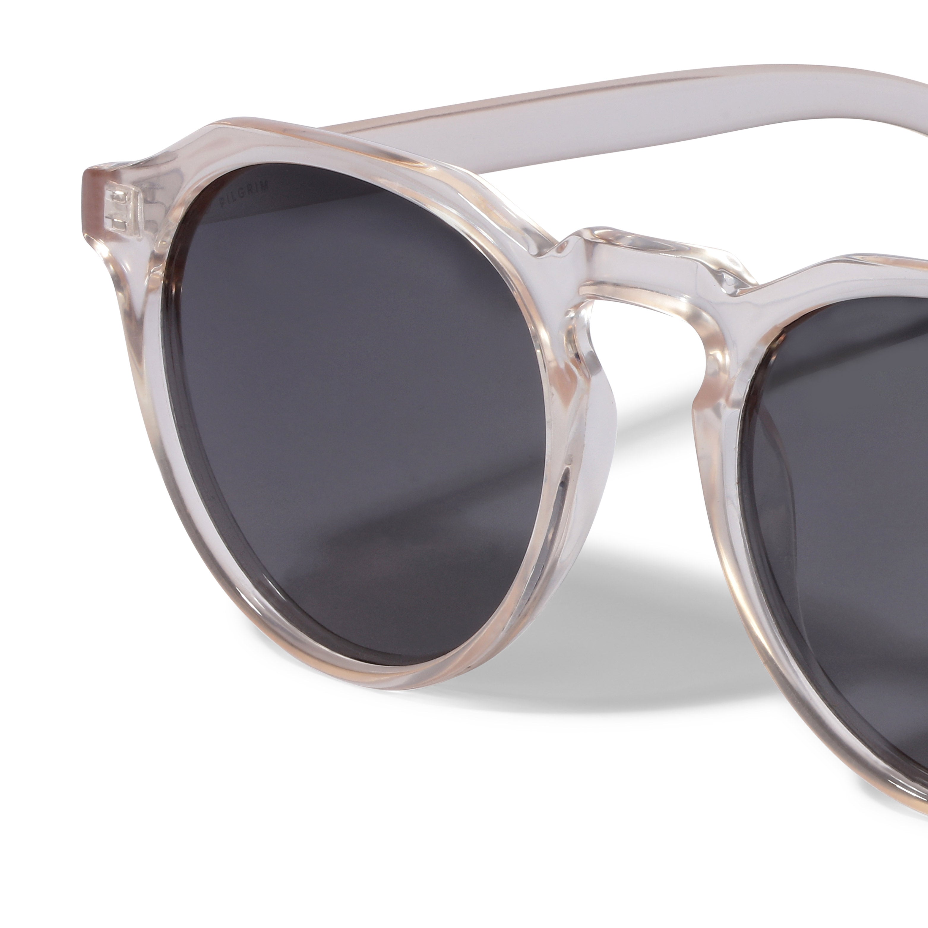 Close-up of ALEJANDRA sunglasses from Pilgrim, featuring transparent frames and smoke-coloured lenses, offering a stylish, modern accessory with UV400 protection.