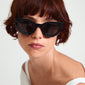 Woman with short red hair wearing the ALONDRA black cat-eye sunglasses, showcasing their unique melting design and trendy style from Pilgrim.