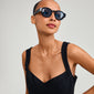 Woman wearing ARIAH sunglasses with super-wide temples and blue lenses, embodying cool vibes and energy. Made from recycled plastic, offering UVA/UVB protection.