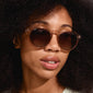 Woman wearing ALEJANDRA sunglasses in transparent brown with a unique round-angular design, exuding a cool, stylish vibe.