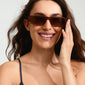 Woman smiling in ALAYNA sunglasses with wide chunky temples and slim, angular frame, embodying edgy, urban style. Perfect for a trendy summer look.