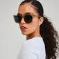 KATYA sunglasses light brown, featuring transparent brown frames and dark green lenses, worn by a woman. Perfect for stylish summer events. UVA/UVB protection with UV400 lenses.