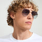 ANA sunglasses by Pilgrim, featuring a sleek Pilot-style metal frame with a trendy angular shape, worn by a man with curly hair and sunglasses.