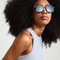 AYLIN sunglasses grey/gold with oversized smoke-coloured lenses and sleek gold temples, worn by a woman with a big afro, embodying a 70s-inspired diva style.