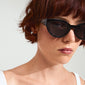 A woman wearing AUBREE sunglasses black/crystal, featuring a sleek cat-eye design with sparkling crystals, embodying Pilgrim's blend of timeless and trendy style.