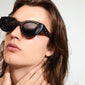 A woman models AUBREE sunglasses, featuring a sleek black cat-eye frame adorned with sparkling Preciosa crystals, embodying a chic and sophisticated look.