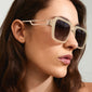 Woman wearing ADDILYN sunglasses with oversized square frame and metal temples, embodying a retro vibe. A stylish accessory from Pilgrim with UVA/UVB protection.