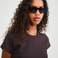 A woman wearing the ALEXIA sunglasses black by Pilgrim, featuring a sleek, ultra-angular metal frame, embodying modern urban style with dark lenses.