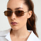 Woman wearing AMIYAH sunglasses with brown lenses and silver metal frame from Pilgrim, highlighting the chic, edgy design ideal for summer style.